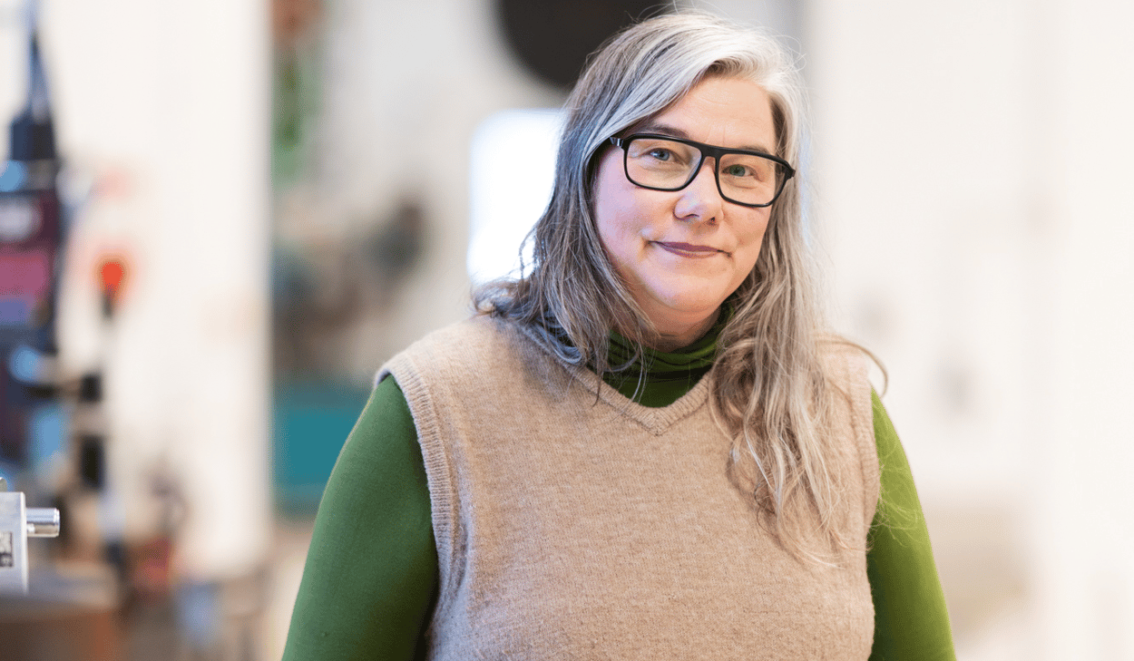 En kvinna som står i en fabrik med händerna på höfterna.