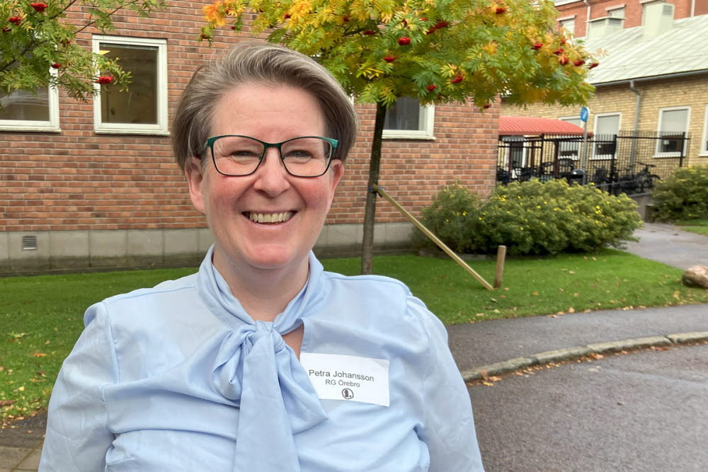Porträtt av en person med namnbricka som visar ”Petra Johansson, RG Örebro”, utomhus framför en tegelbyggnad.