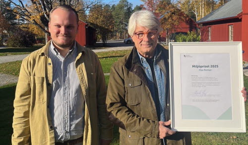 Två män står bredvid varandra i utomhusmiljö på hösten. Den ena håller i ett inramat diplom för Miljöpriset 2025.